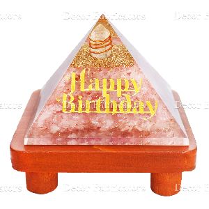 Rose Stone Orgone Vastu Pyramid with Golden Happy Birthday Symbol On a Brown Wooden Stand