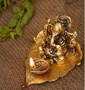 handcrafted Ganesh statues on leaf with diya